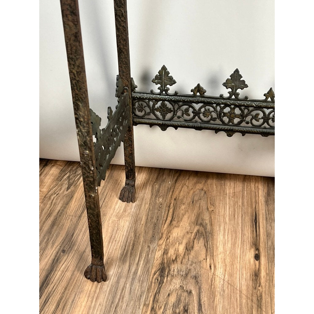 Close-up of an Antique Gothic Revival Cast Iron and Brass Phone Stand (attr. Oscar Bach or Bertram Segar, c.1920 Greenwich Village), showing ornate clawed feet and filigree legs on a wooden floor against a white background. Brand: None/Unknown.