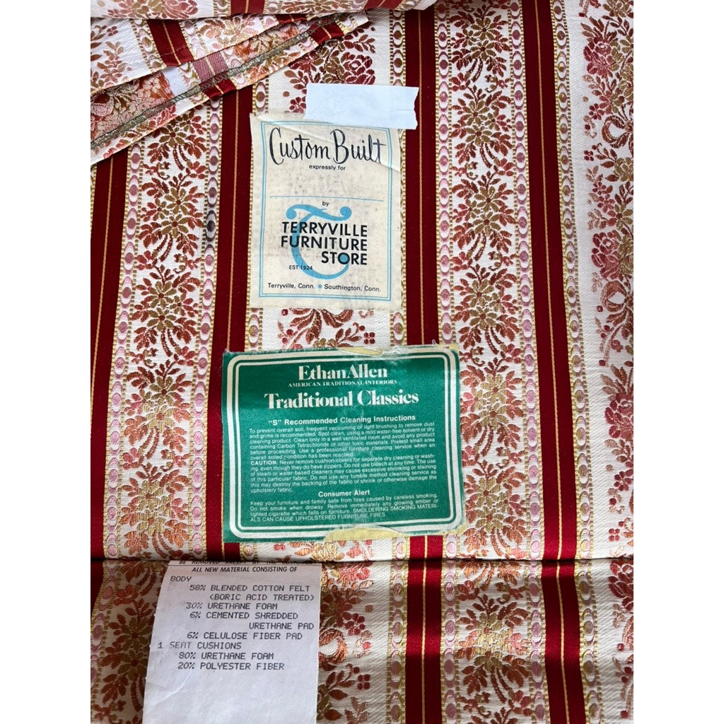 Three fabric tags on a Vintage Chippendale Style Wingback Chair by Ethan Allen display "Custom Built," "Terryville Furniture Store," "Ethan Allen Traditional Classics," and a material content label.
