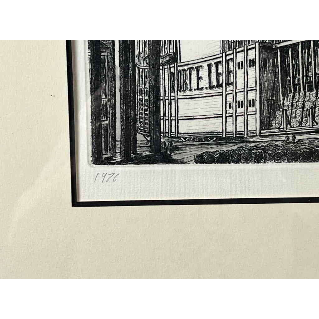 A close-up of the framed etching “Steamboat Robert E. Lee” by Alan Jay Gaines reveals part of a building with vertical beams and the partial word HOTEL; 1972 is handwritten in pencil beneath the artwork.