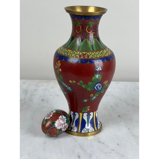 The Vintage Chinese Cloisonné Vase and Egg from Pearl City Antiques features a red vase with colorful floral patterns and gold trim, displayed on a marble surface beside the matching decorative egg—both showcasing exquisite enamel artistry and intricate floral designs.