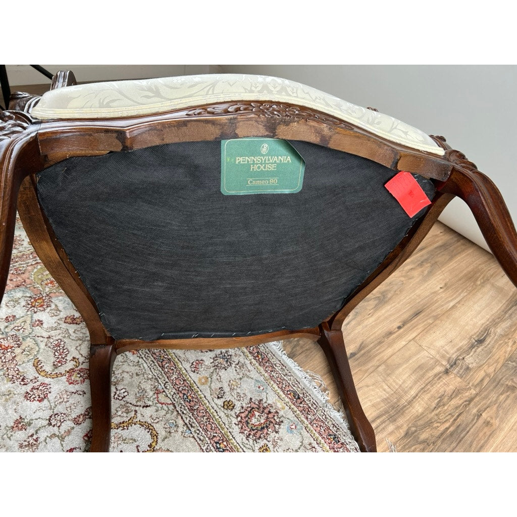 The underside of the Vintage Louis XV Style Fauteuil Arm Chair by Pennsylvania House is shown, featuring a green Pennsylvania House label and red tag. The arm chair sits on a floral-patterned rug over a wooden floor.
