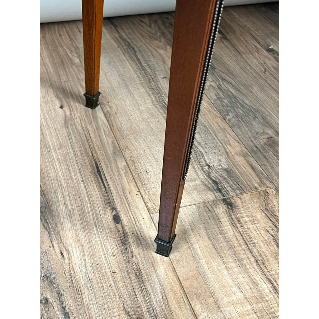 Two mahogany legs with metal feet from an Antique French Louis XVI-Style Mahogany Marble Top Bouillotte Table (early 20th century) are shown on a light brown wood-grain floor. Photo is taken from above, highlighting the legs and floor texture. Brand unknown.