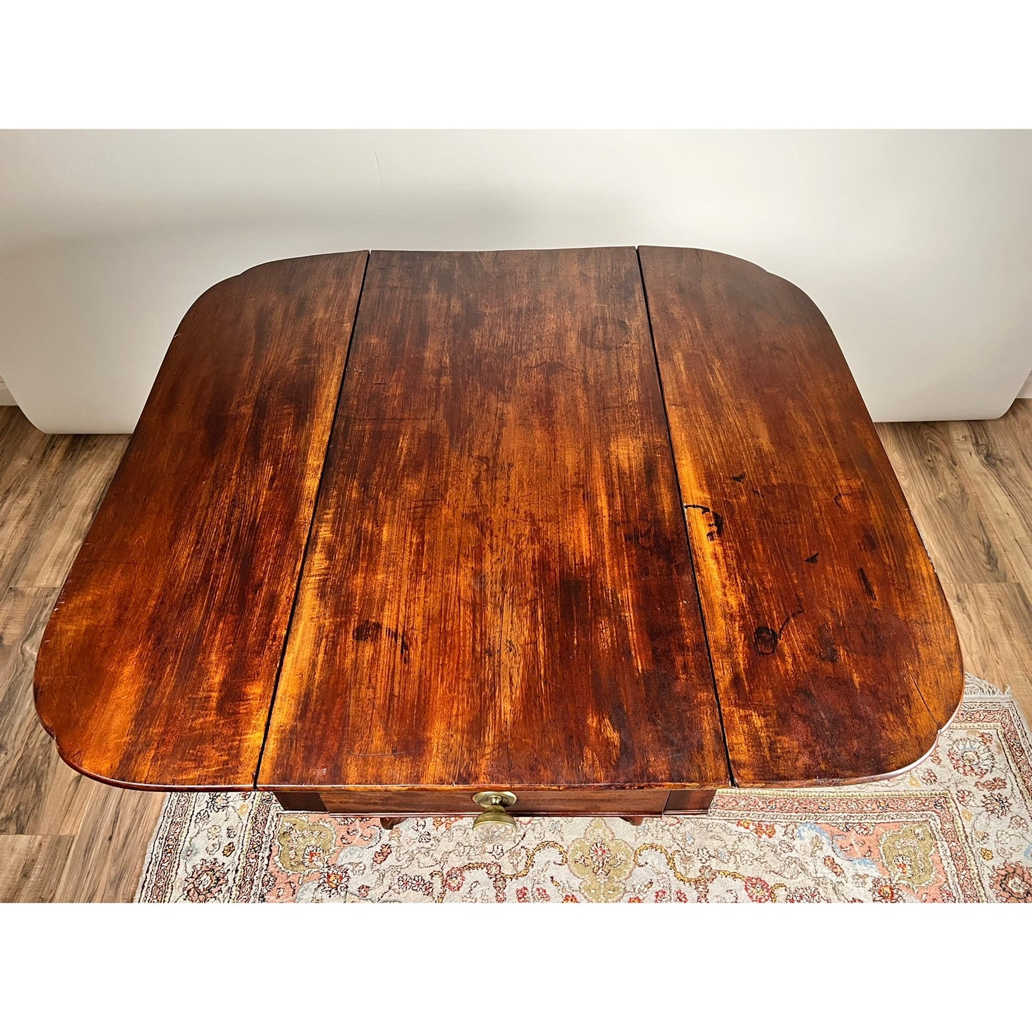 An Antique American Empire Drop Leaf Table c. 1840 features great eagle carved feet, a rich dark finish, visible wood grain, and some wear; it sits on a patterned rug over a wood floor. Brand: None/Unknown.