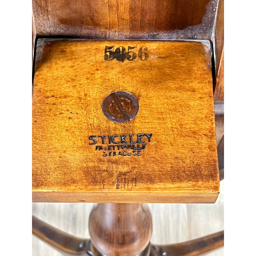 Close-up of Stickley’s Vintage Federal Style Cherry Octagonal Tilt Top Candlestand, featuring a round Stickley logo stamp, the brand name, details like Fayetteville Syracuse, and the number 5056 stamped above.
