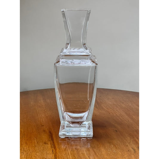 A Vintage Baccarat Crystal Pearl Vase from Pearl City Antiques, featuring elegant French design with its clear crystal form and sophisticated silhouette, sits atop a wooden surface against a plain, light gray background.