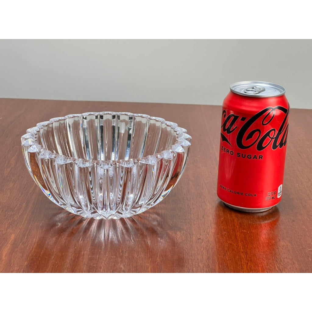 A Vintage Tiffany & Co. Crystal Bowl in a ribbed petal design sits on a wooden surface next to a red can of Coca-Cola Zero Sugar, offering classic elegance.