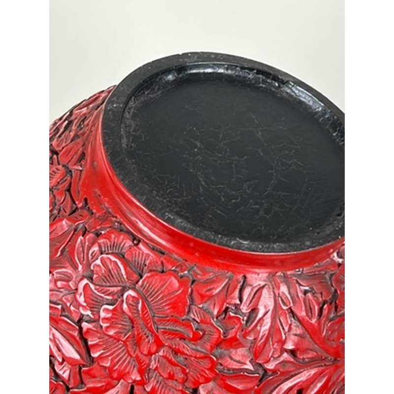 Close-up of the base of an Antique Chinese Hand-Carved Cinnabar Lacquered Lidded Jar, probably Qianlong, showing intricate raised floral and leaf designs on a detailed surface with a black, slightly worn circular bottom.