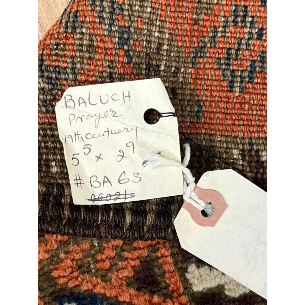 A handwritten tag on this Antique Timuri Baluch Prayer Rug with repeating mihrab design, c. 19th century (2’9 x 5’5), notes its origin; the rug displays brown, orange, and blue geometric patterns typical of Baluch weavings.