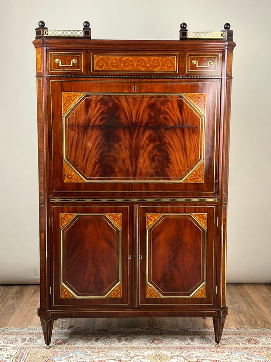 The Secrétaire à abattant d'époque French Louis XVI Style Secretary by Pearl City Antiques features intricate inlay, brass accents, and geometric designs. This elegant late 19th-century piece stands on tapered legs atop a patterned rug.
