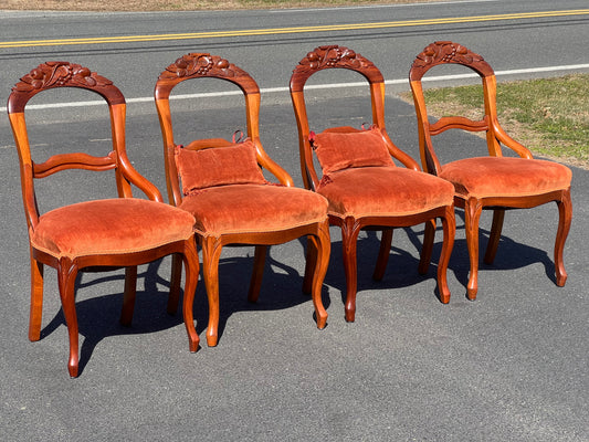 Four Great Mahogany Victorian Side Chairs by Pearl City Antiques, featuring red upholstered seats, are arranged in a row outdoors on a paved surface with grass and a road in the background.
