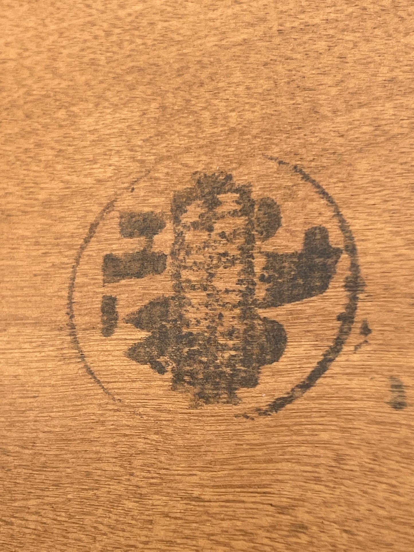 A black circular stamp, now worn and faded, appears on the wood of a Mid-Century Modern Birch and Rattan Accessory Table by Heywood Wakefield from Pearl City Antiques, making any original markings or symbols hard to discern.