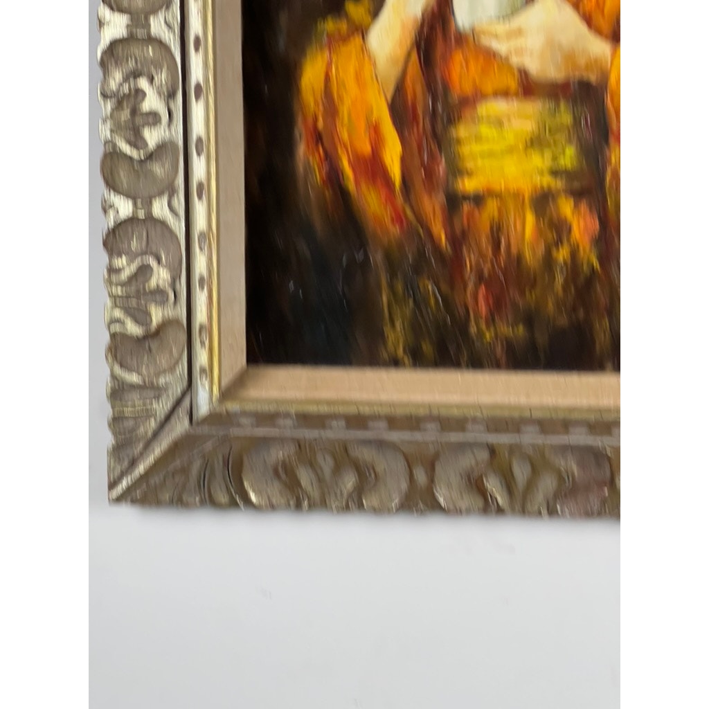 Close-up of the ornate gold frame and vivid colors from the vintage mid-century oil painting “Girl in Kimono” signed Korim, featuring part of a figure in orange and yellow against a dark background. Brand unknown.