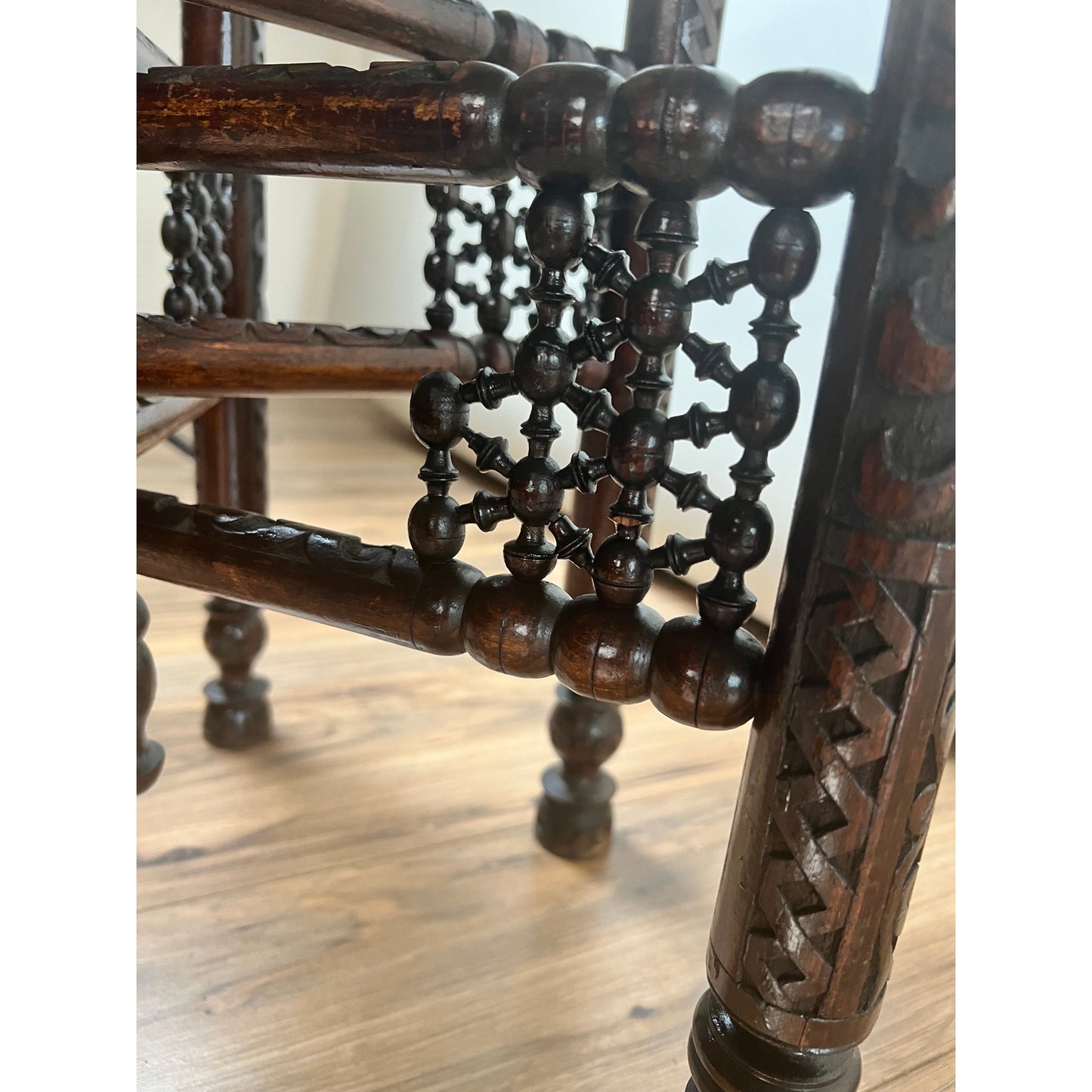 Close-up of intricately carved legs and decorative spindles from a Moroccan or Syrian Moorish folding tray table, shown on a light wood floor. The craftsmanship showcases geometric and floral motifs evocative of traditional Moorish artistry.
