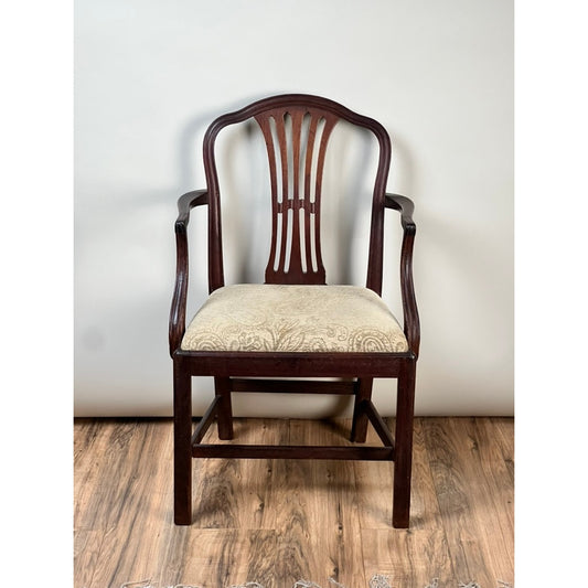 The Antique English George III Mahogany Hepplewhite Armchair by Pearl City Antiques, dating from the early 19th century, showcases an ornate backrest and a cushioned seat upholstered in beige patterned fabric, elegantly positioned on a wooden floor against a plain light background.