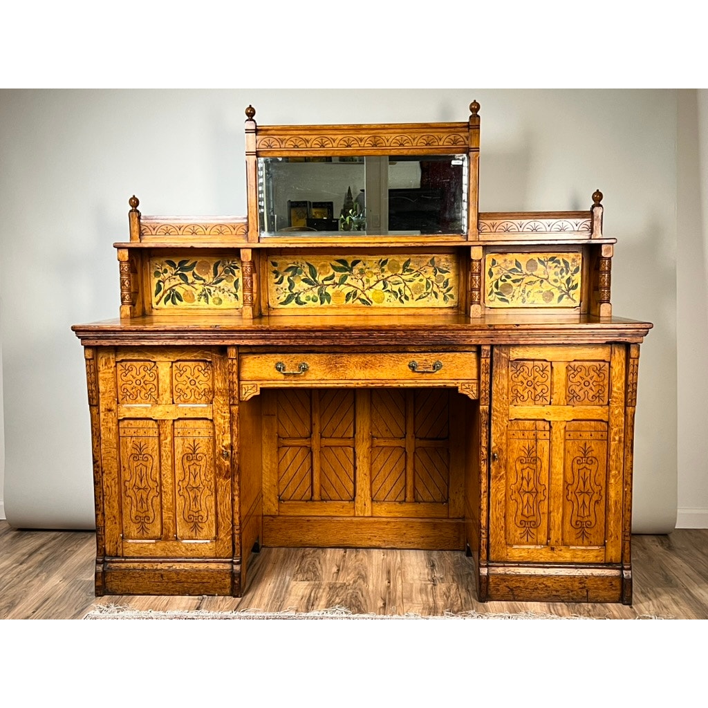 An Antique Victorian Aesthetic Movement oak desk in its original finish from the late 19th century, featuring intricate carvings, stained glass floral panels, a central mirror, multiple drawers, and cabinets. Brand unknown.