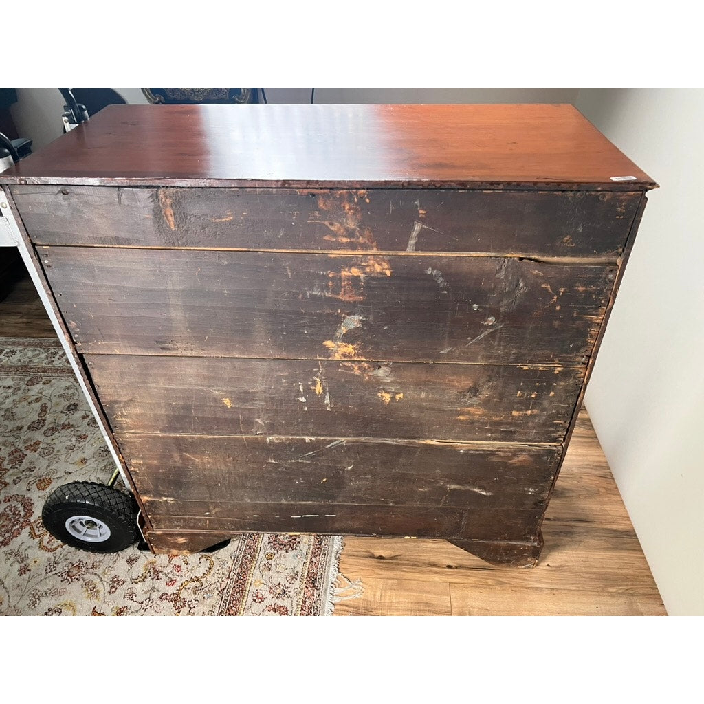 An Antique Chippendale Pine Graduated Four Drawer Chest, attributed to a Northampton, MA maker from the late 18th century, stands on a hardwood floor near a patterned rug; a hand truck with wheels is visible on the left.