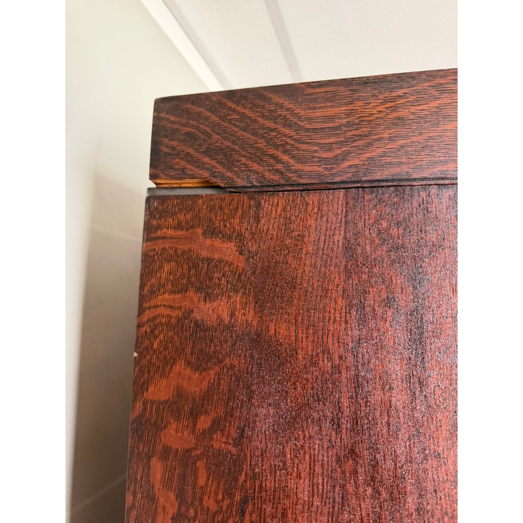 Close-up of a Camden Cabinet Company Antique Hale System Quarter-Sawn Oak Five-Stack Barrister Bookcase corner, c. 1910, showing a slight gap and misalignment between the top and side panels. The quarter-sawn oak features a reddish-brown finish with a visible grain pattern characteristic of its antique design.
