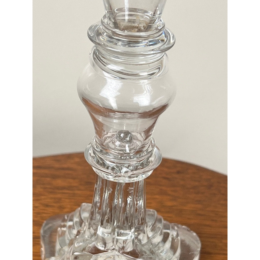 A close-up of an Antique Sandwich Glass Whale Oil Lamp c. 1840 with intricate detailing and reflections, set on a wooden surface against a neutral background. Brand: Unknown.