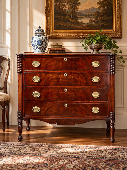 An Antique Sheraton Mahogany Cookie Corner Four Drawer Chest c. Mid 19th Century featuring dark wood, four drawers with brass pulls, topped with a blue and white lidded jar, stacked books, and a potted plant.