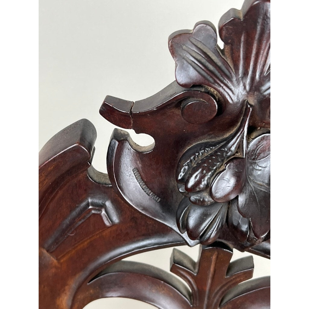 Close-up of an Antique Victorian Rococo Revival Carved Walnut Slipper Chair back, c. Late 19th Century, showcasing intricate floral and leaf carvings with a dark polished finish and a floral needlepoint seat. Brand: None/Unknown.