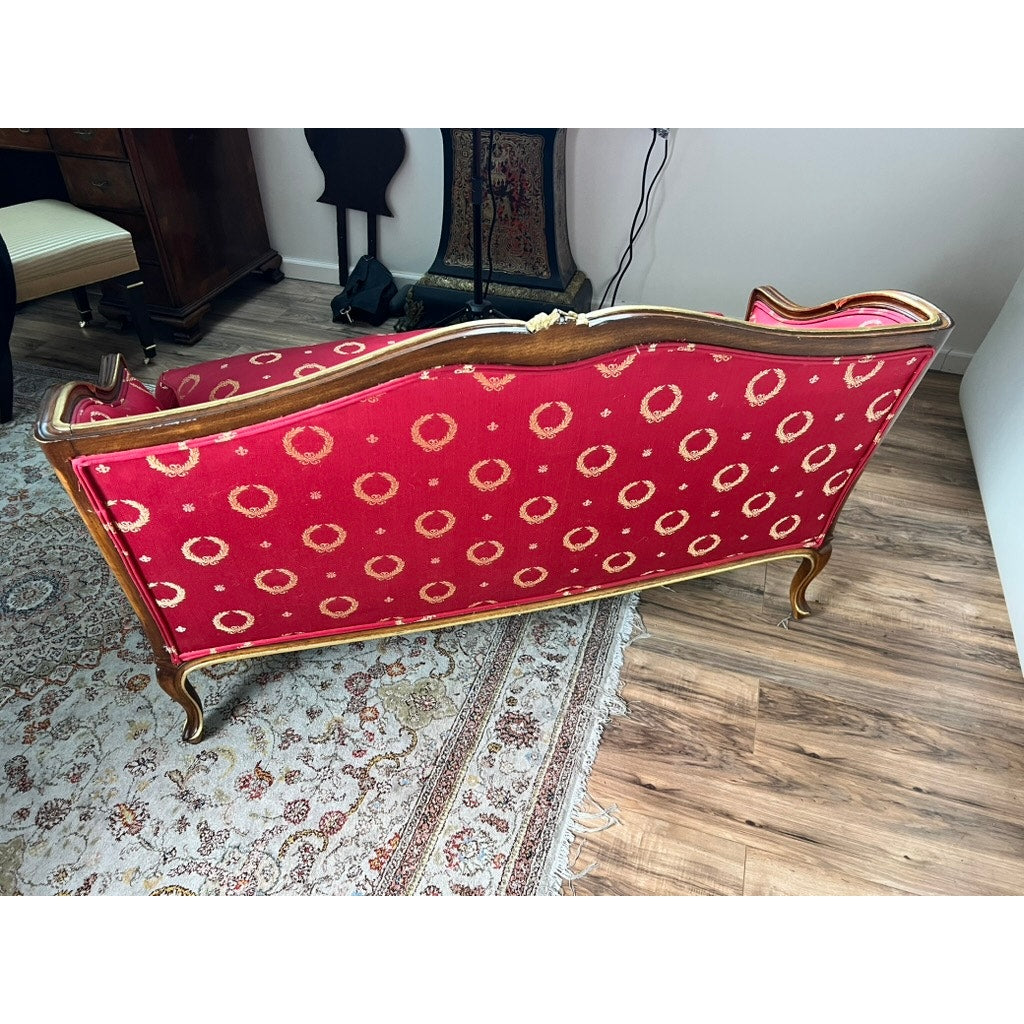 A Vintage French Regency Style Custom Upholstered Settee with red fabric and a giltwood frame, featuring a circular back pattern, sits on a patterned rug over a wooden floor among various furniture pieces.