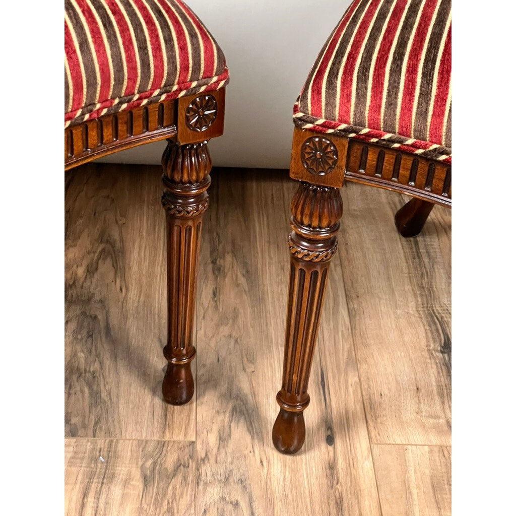 A vintage pair of Ardley Hall Wheel Back Side Chairs with ornate carved legs and red-and-gold striped upholstery sit on a wooden floor, with part of a light-colored wall or furniture in the background.