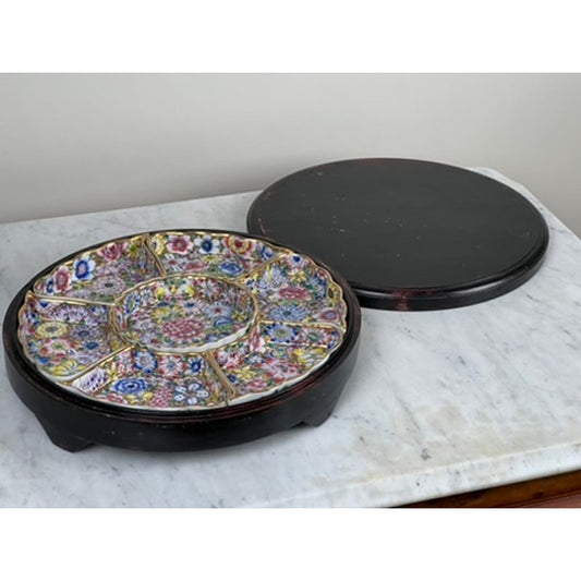 A Vintage Chinese Canton Sweet Meat Set with Case by Pearl City Antiques, dating to the early 20th century, rests atop a marble surface. The round, sectioned famille rose porcelain dish features vibrant floral designs and sits gracefully in its dark wooden base; the matching lid is placed alongside—an exquisite antique collectible.