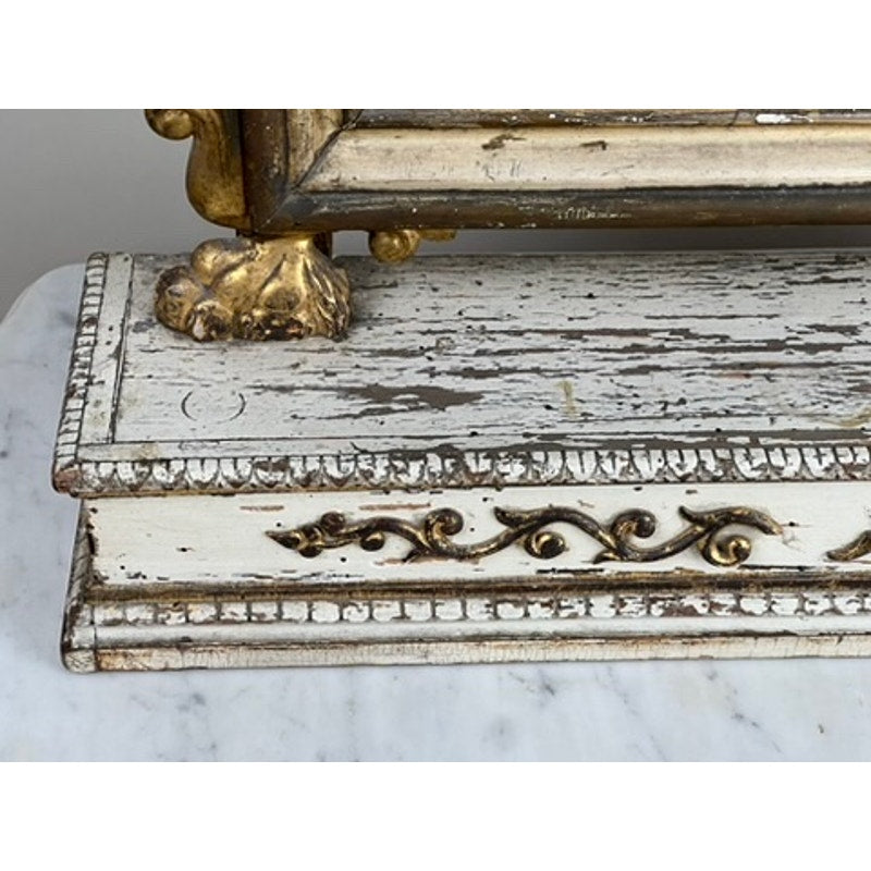 A close-up of an Antique French Empire Gilt Wood Vanity or Table Mirror c. Mid 19th Century showcases ornate gold detailing and claw feet on a white marble surface, with chipped paint that reveals its neoclassical antique charm.