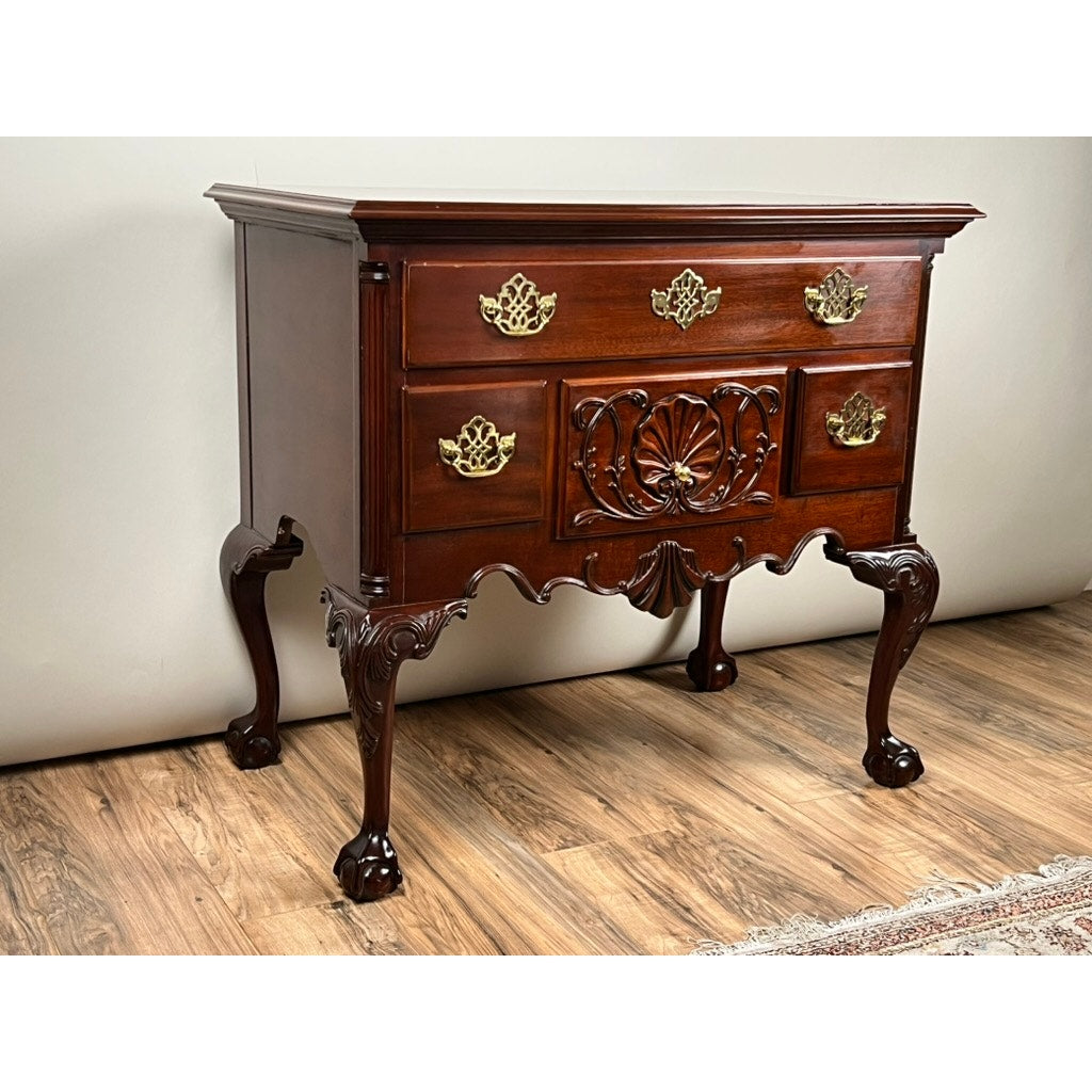The Vintage Solid Mahogany Chippendale Style Lowboy by Councill Craftsmen features ornate brass handles, carved details, and cabriole legs. This Councill Craftsmen piece sits on a hardwood floor beside a patterned rug.