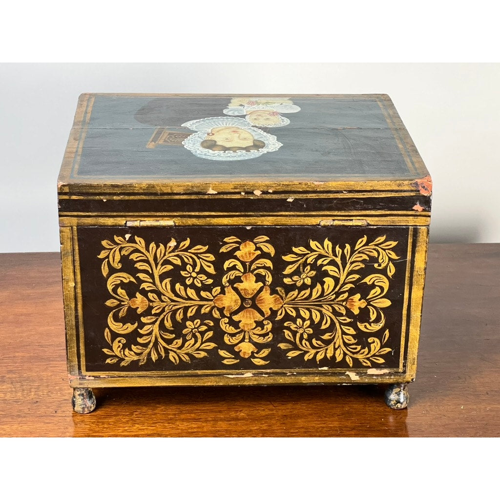 An Antique New England Folk Art Painted Portrait Document Box, c. 1840–1860, features ornate gold floral designs and a hand-painted image of a mother and child on the lid—a charming example of mid-19th century American decorative art.