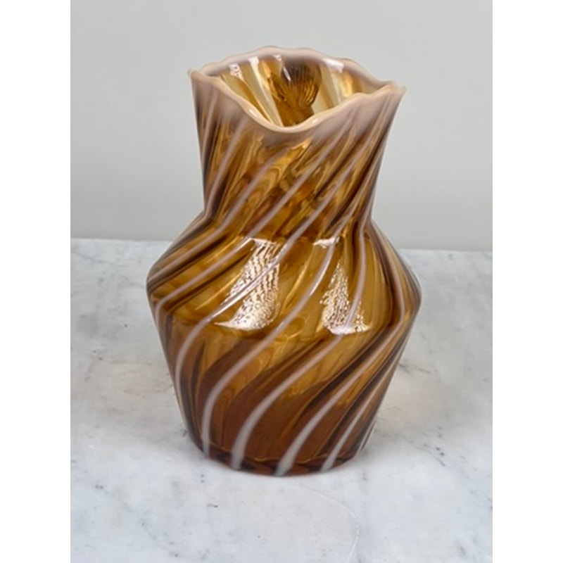 A vintage collectible, the Fenton Autumn Gold Opalescent Glass Spiral Pattern Pitcher with a wavy rim and geometric shape sits on a marble surface against a plain light background.