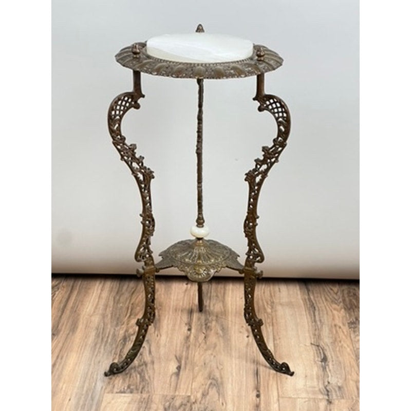 An Antique Victorian Bronze and Onyx Stand from the late 19th century features decorative bronze legs, a round onyx top, and ornate detailing. It stands on a wood floor against a plain background. Brand is unknown.