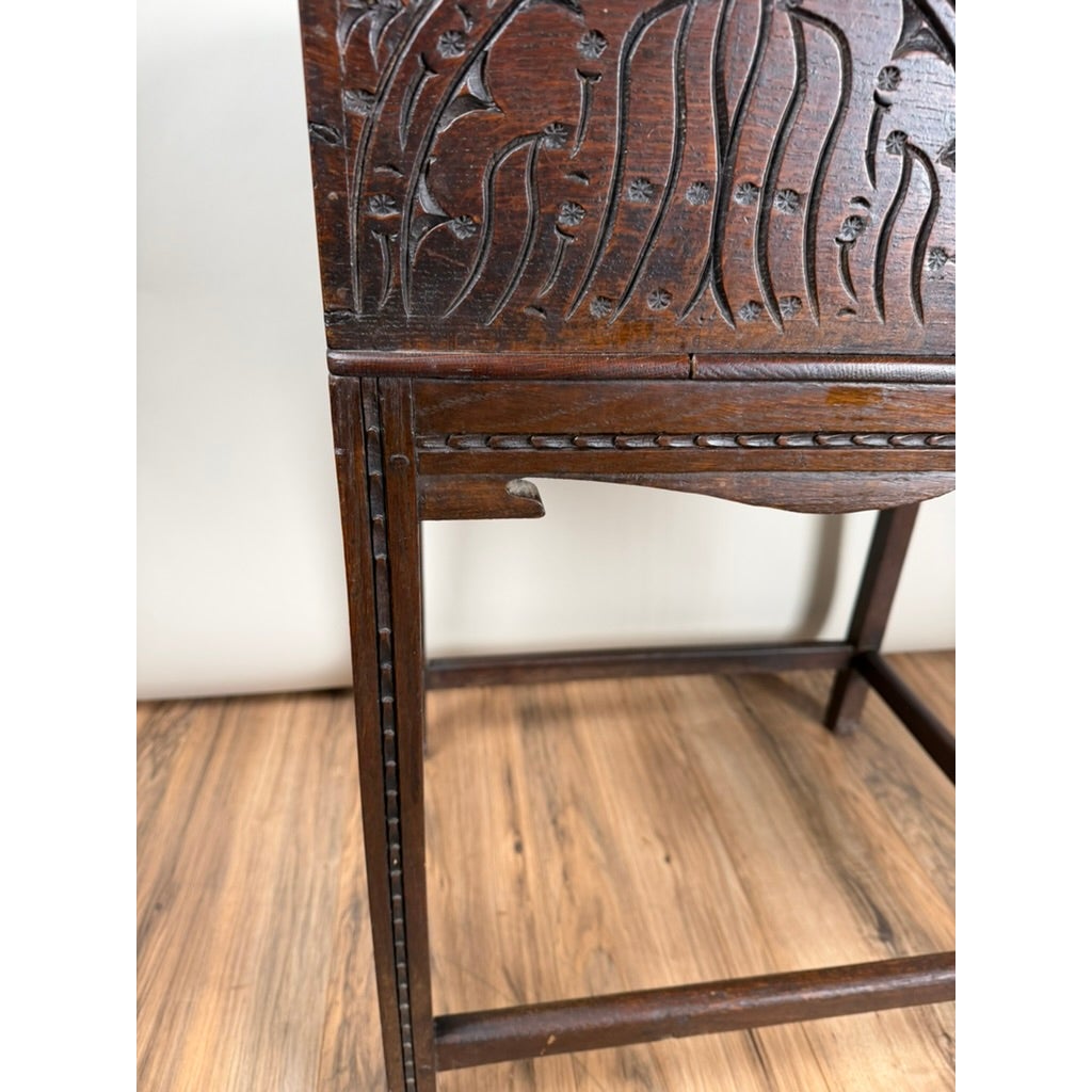 English Jacobean Carved Oak Bible Box on Later Stand, c. Late 17th Century, featuring ornate floral carvings on a simple wooden stand with thin legs.