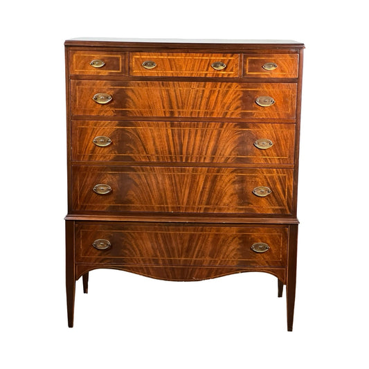 A vintage Dutch Woodcraft Shops Federal Style Flame Mahogany Chest on Stand, crafted circa 1945–1955, featuring six drawers with brass handles, elegant flame mahogany grain patterns, and classic tapered legs with curved details that showcase the timeless craftsmanship of Dutch Woodcraft Shops.