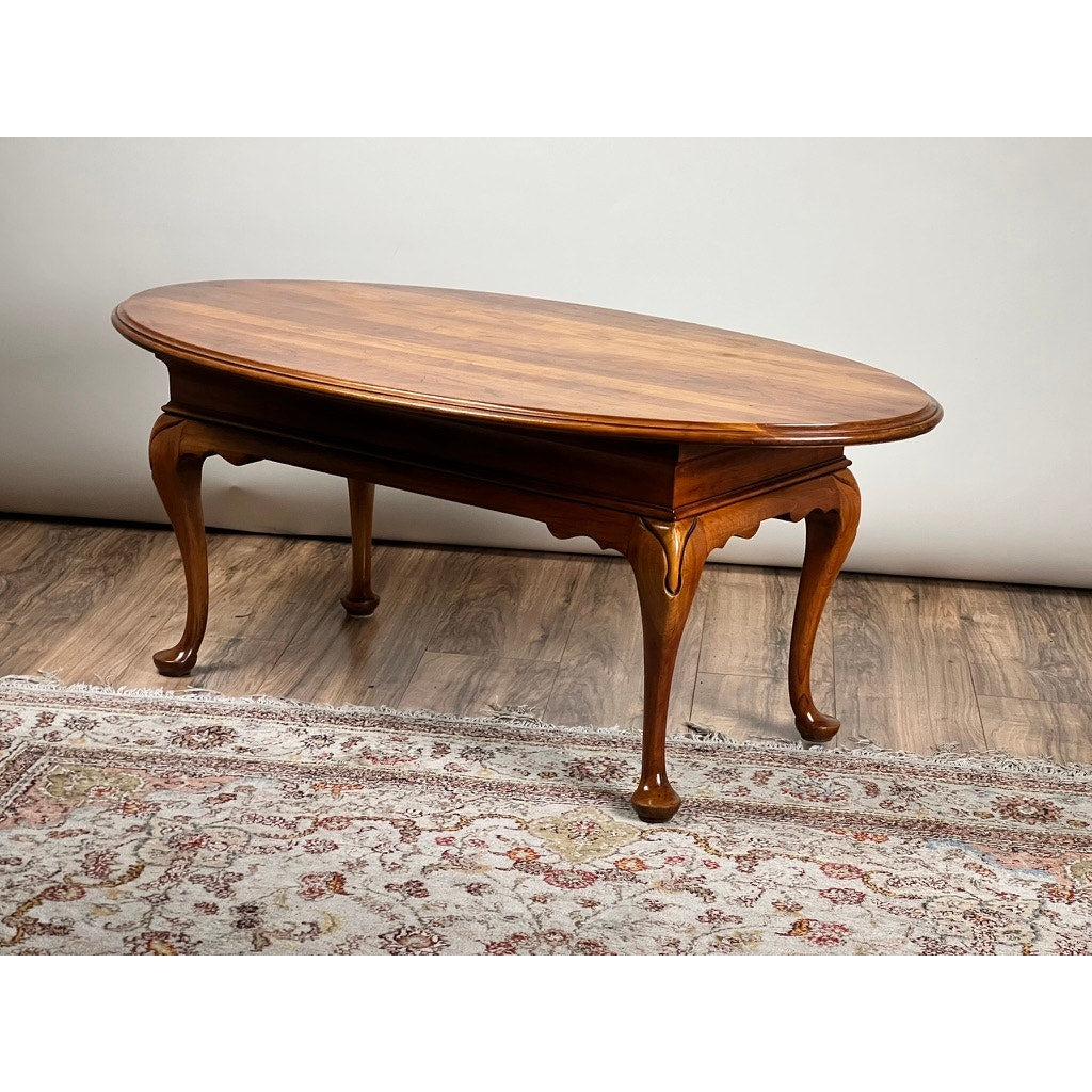 A Vintage Solid Cherry Queen Anne Style Coffee Table, attributed to Pennsylvania House, stands on a patterned rug atop a wood floor against a plain light-colored wall.
