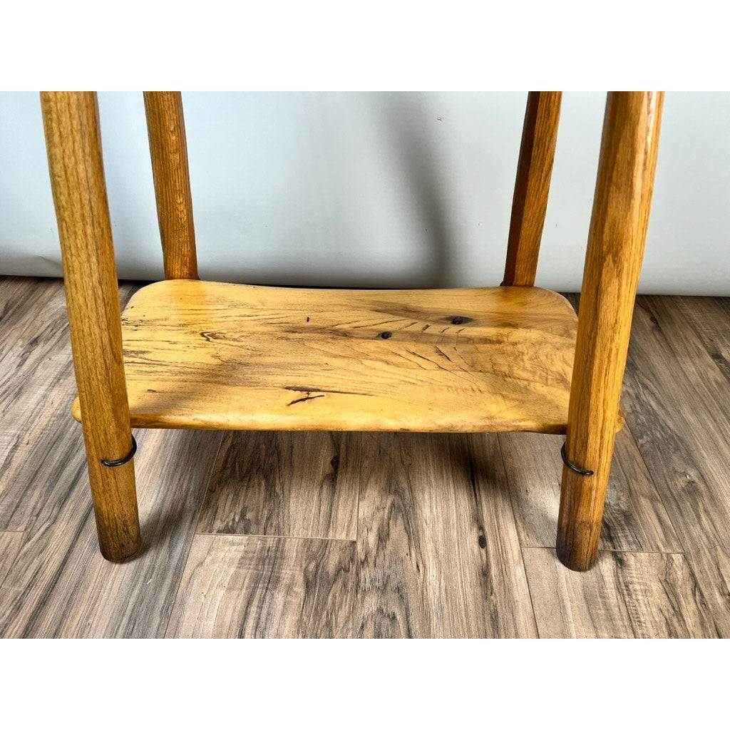 A close-up of the lower wooden shelf and legs of the Vintage Wabi Sabi Bench from spalted maple, signed Neil Panyik, shows its handcrafted natural finish with visible grain and knots on a wood-patterned floor.