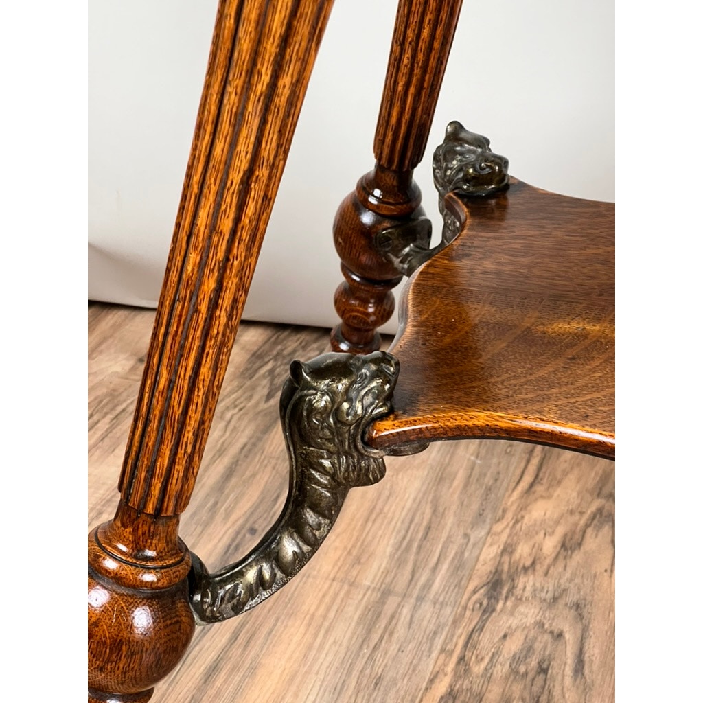 Close-up of the Antique Victorian Oak Lamp Stand with Bronze Lions Head Mountings (c. late 19th century), showing its ornate carved table leg and bronze lion’s head and paw detail, set on a hardwood floor with a light background.