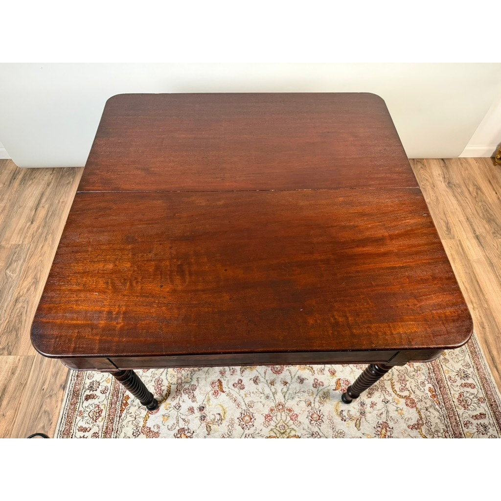 A Pearl City Antiques American Classical Mahogany Single Drop-Leaf Table with Spiral-Twist Legs (c. 1830–1845) sits on a patterned rug over a wood floor, viewed from above. Reminiscent of early 19th-century craftsmanship, its rich brown finish, slightly rounded corners, and visible wood grain evoke the elegance of classical design.