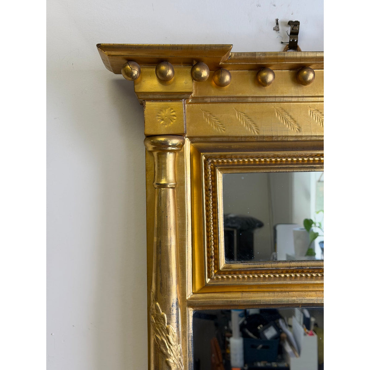Close-up of the upper left corner of an American Federal Giltwood Two-Plate Looking Glass, featuring a cornice with ball ornaments and a fluted column side.