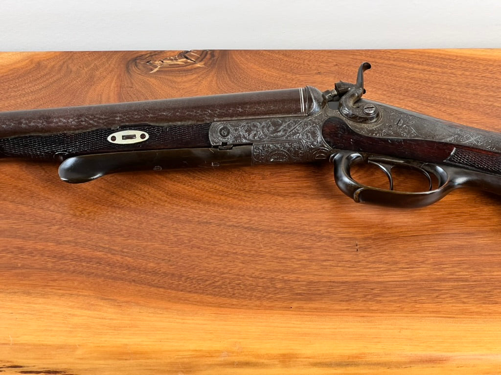 A close-up of an Antique Christoph Funke Suhl German Damascus Double Barrel Hammer Shotgun, c. 1880, with a carved stock and beautifully patterned barrels, displayed on a wooden surface. Offered by Pearl City Antiques, this exceptional piece features ornate engravings and showcases the outstanding craftsmanship of its era.