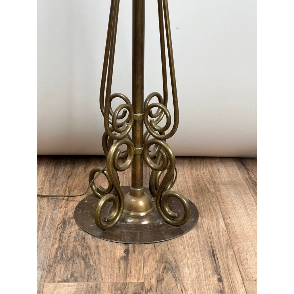 Base of an Antique Art Nouveau Brass Floor Lamp, attributed to Jules Cayette and Charles Schneider c. 1920, featuring ornate swirling metalwork on a circular plate, set on a wooden floor with a neutral background.