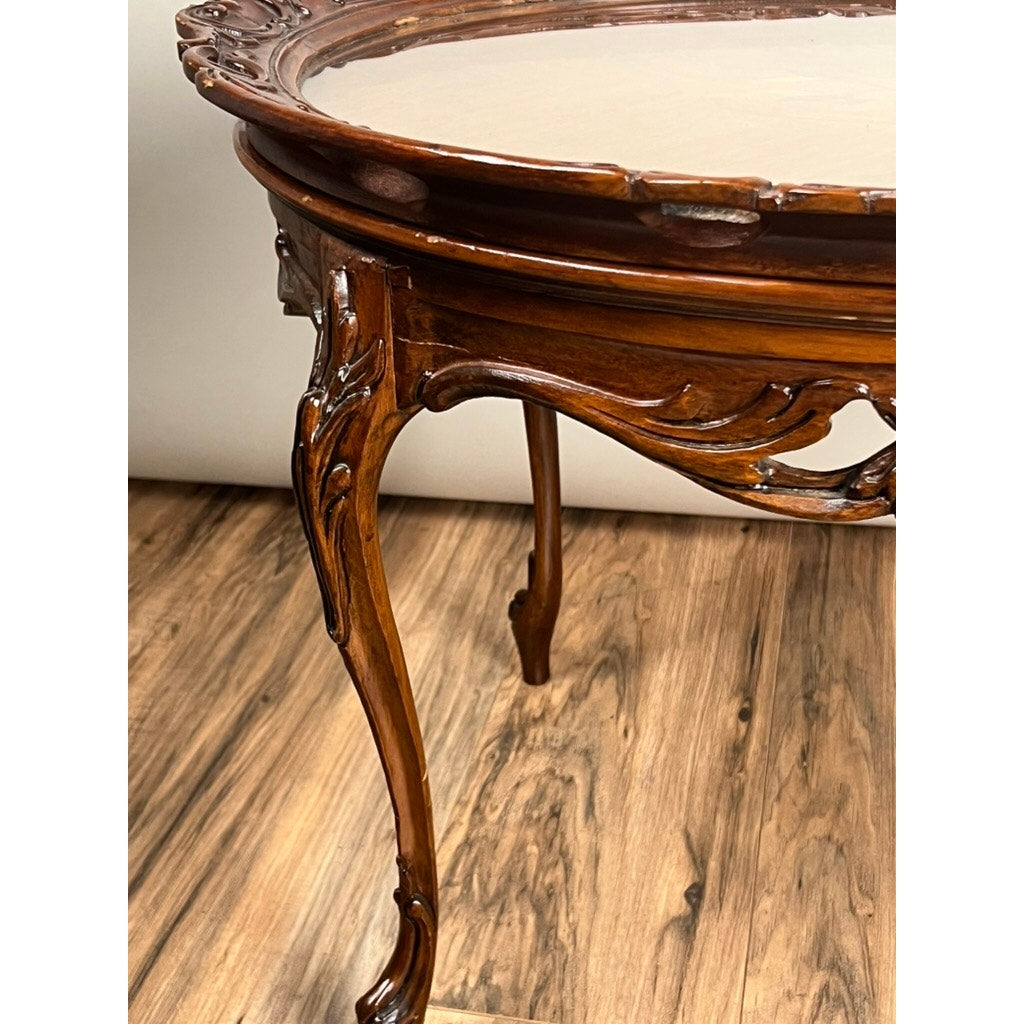 Close-up of a Vintage Louis XVI Style Butlers Table with curved legs, intricate carved details, a glossy finish, and a removable glass tray top, standing on a wood-patterned floor. Brand is unknown.