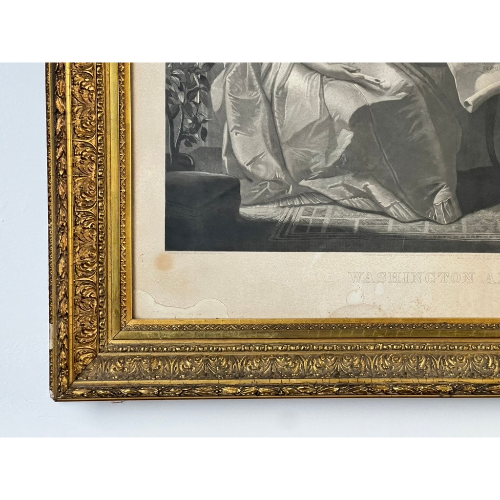 Close-up of an ornate gilt frame housing the antique 1858 engraving “Washington and His Family,” published by Bradley & Co., Philadelphia. The partially visible black-and-white artwork shows the edge of the image with faint “WASHINGTON” text, and some characteristic paper discoloration—a detail evocative of period engravings from the mid-19th century.
