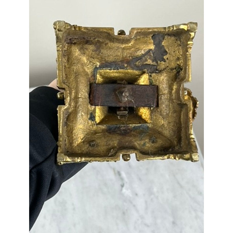 The image shows the underside of an Antique Pair Late 19th Century Brass Three Light Candelabra—square, gold-toned metal with a decorative edge and a tarnished, rusty bracket attached at the center. Brand is unknown.