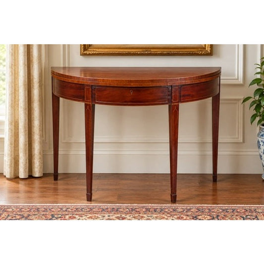 An English George III Mahogany and Satinwood-Inlaid Demilune Games Table, circa 1790–1810, featuring a semicircular top, four tapered legs, and light wood inlay.