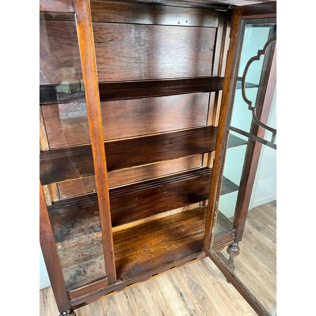 A Depression Era Mahogany Curio Display Cabinet with glass sides, Circa 1930s, is displayed empty on a wood floor. The cabinet showcases rich mahogany tones and intricate detailing on the glass panels, capturing the timeless elegance characteristic of vintage American furniture.