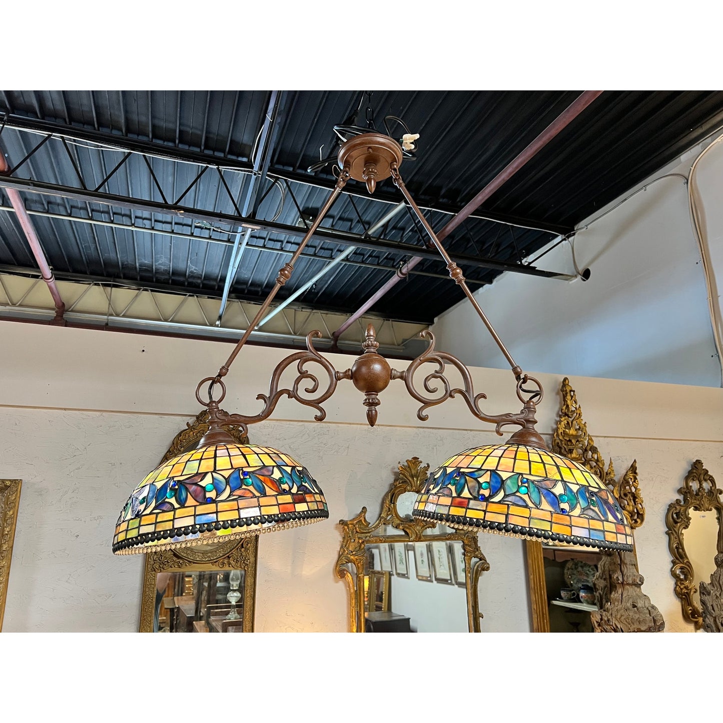 Two Vintage Tiffany Style Leaded Stained Glass Double Pendant Billiard Island Lights with intricate metalwork hang from the ceiling in a room adorned with ornate mirrors and antique furniture, evoking timeless elegance—ideal as an island fixture for the kitchen or as a classic stained glass billiard light.