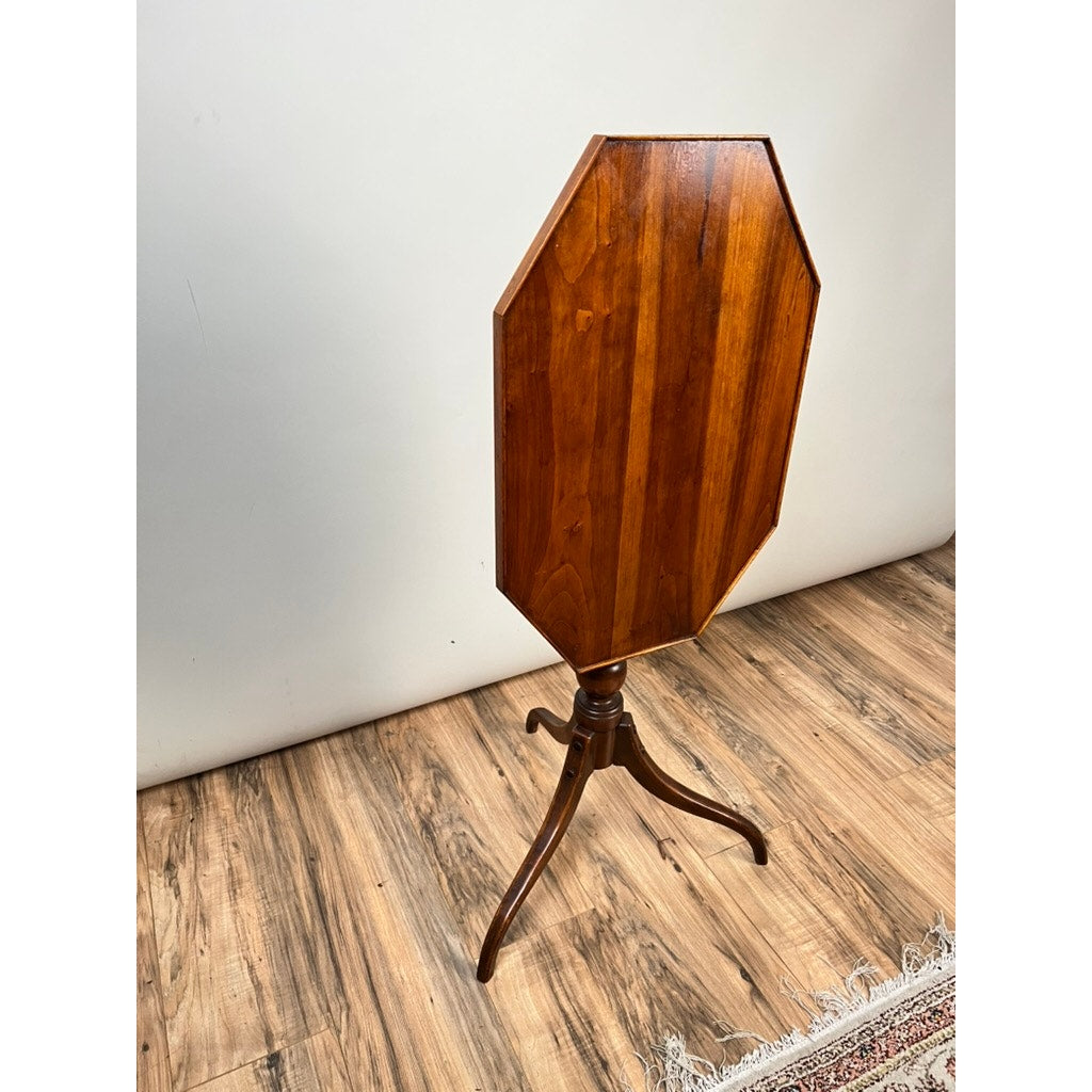 A Stickley Vintage Federal Style Cherry Octagonal Tilt Top Candlestand stands on a wood-patterned floor against a plain white wall, with part of a decorative rug visible at the bottom right.