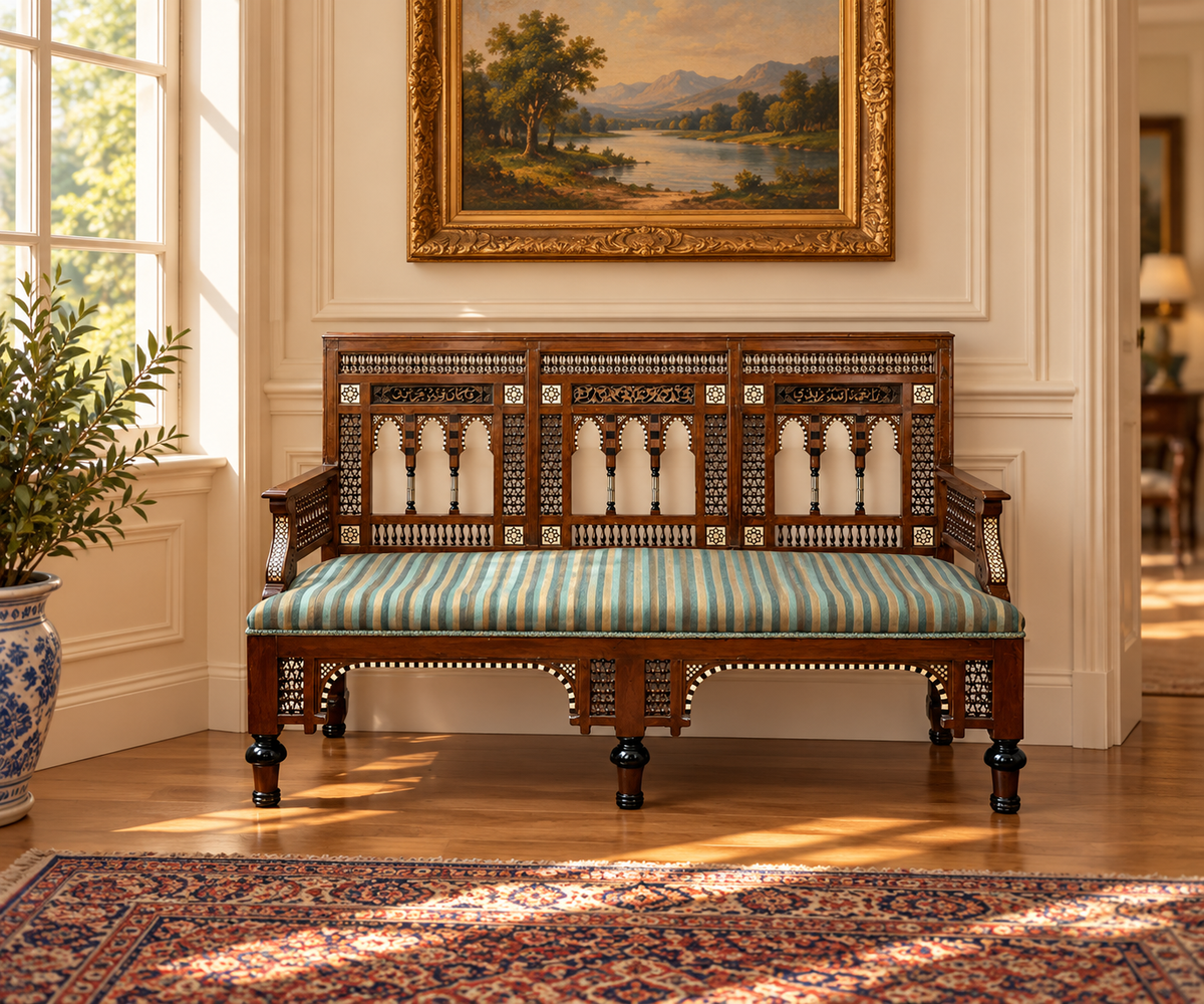 Pearl City Antiques Early 20th Century Moorish Settee with Bone and Mother of Pearl Inlay, featuring intricate wooden carvings and a blue and white striped cushion.