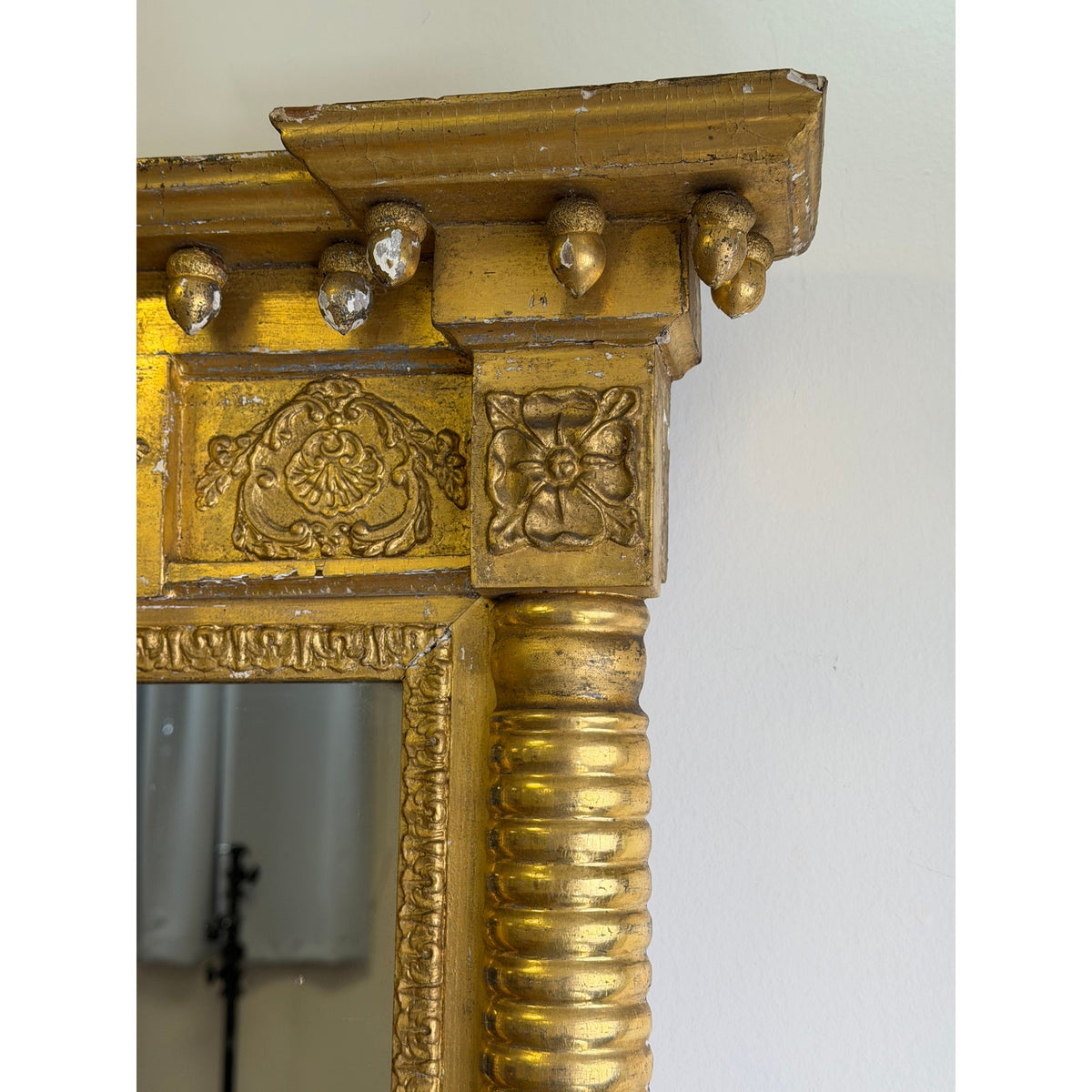 Close-up of the gilded wooden frame of an American Federal Giltwood Pier Mirror, featuring an ornate cornice, carved floral corner blocks, and column side detail.